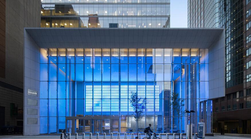 Riding cyclist in front of the entrance to a modern glass building